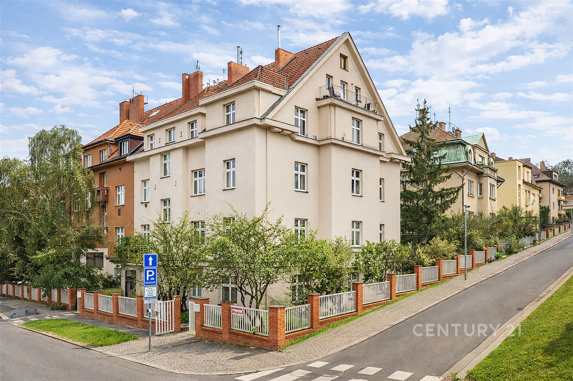 Vícepatrový činžovní dům s klasickou fasádou, šikmou střechou a zahradou; klidná ulice, rezidenční čtvrť vhodná pro rodiny.