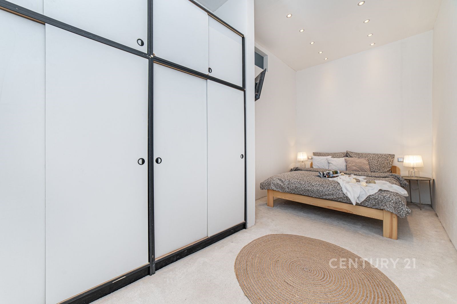 Prostorná ložnice s vestavěnými skříněmi, moderním osvětlením a kobercem, nabízí útulný a čistý design ideální pro relaxaci.