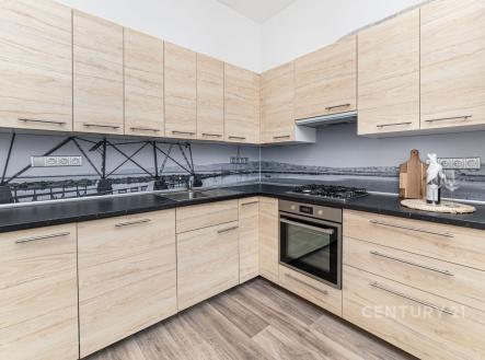 Moderní kuchyň s dřevěnou pracovní deskou, vestavěnými skříněmi a parketovou podlahou, světlé dřevo a elegantní design zajišťují atraktivitu.