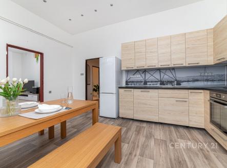 Moderní kuchyň s dřevěnou podlahou, vestavěné skříně a světlý design.