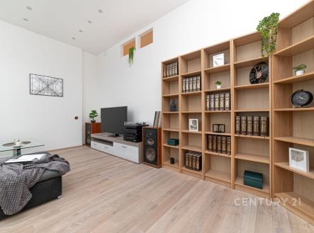 Obývací pokoj s parketovou podlahou, velká knihovna a moderní nábytek, světlý prostor s minimalistickým designem.
