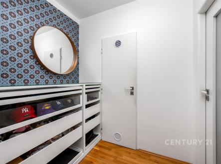 Vstupní předsíň s parketovou podlahou, vestavěnými skříněmi a stylovou tapetou nabízí moderní a praktický prostor.