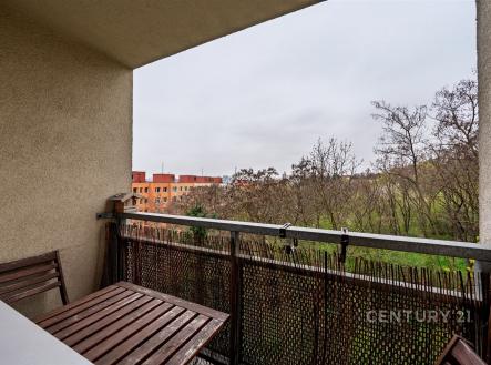 Balkón s výhledem do přírody, vybavený dřevěným nábytkem, působí útulně. Skvělá lokalita pro relaxaci, ideální pro moderní bydlení.