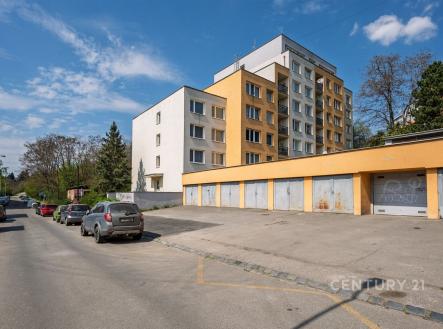 Vícepodlažní bytový dům s moderní fasádou, parkování před garážemi, klidná rezidenční lokalita, blízko zeleně a s dobrou dopravní dostupností.
