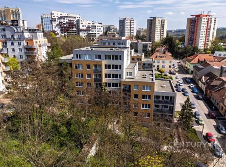 Pohled na bytový dům v rezidenční části města, moderní architektura, světlé fasády, okolní zeleň dodává klidnou atmosféru