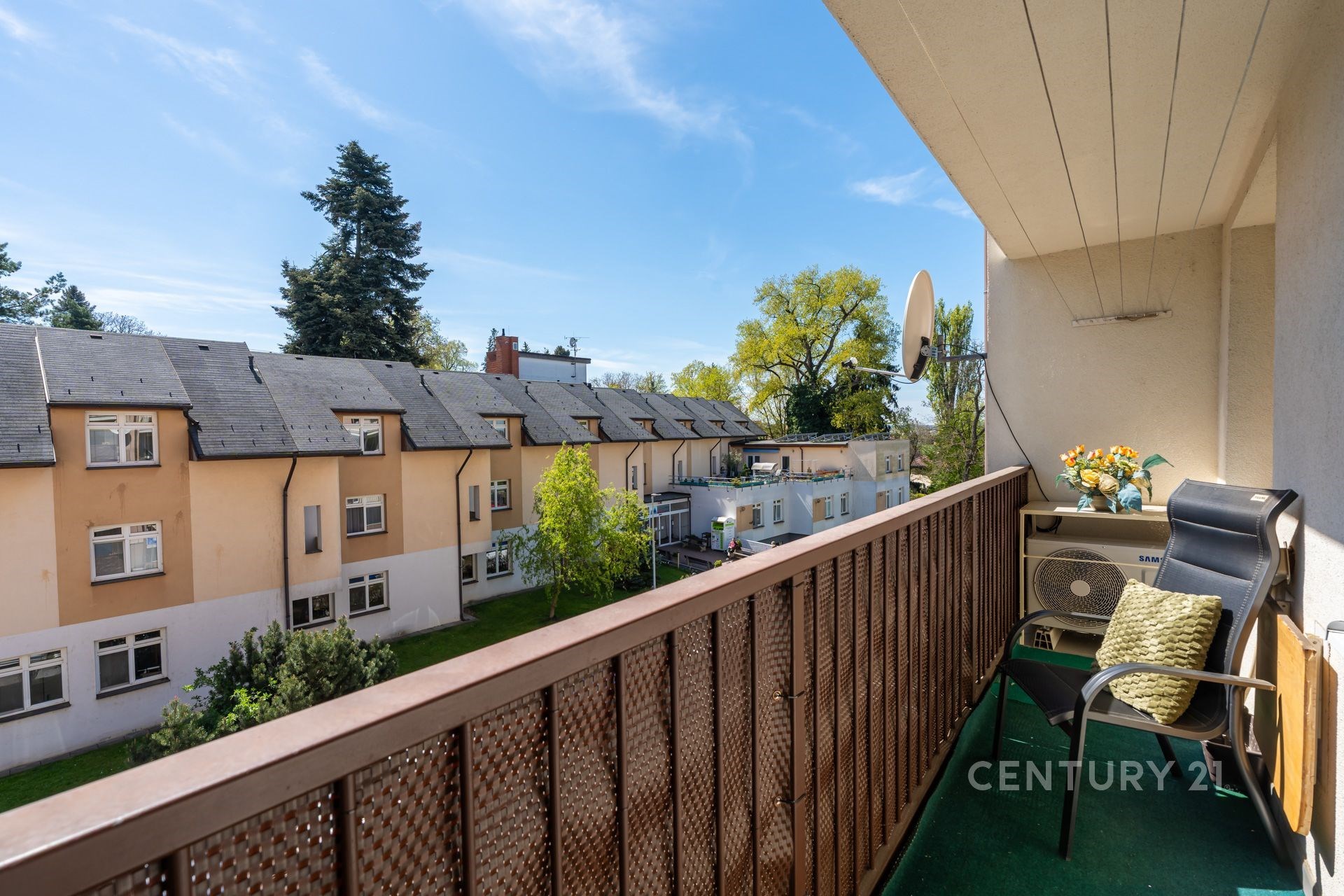Útulný balkon s výhledem, dřevěné zábradlí, částečně krytý prostor, ideální pro relaxaci, klidná lokalita, upravené okolí.