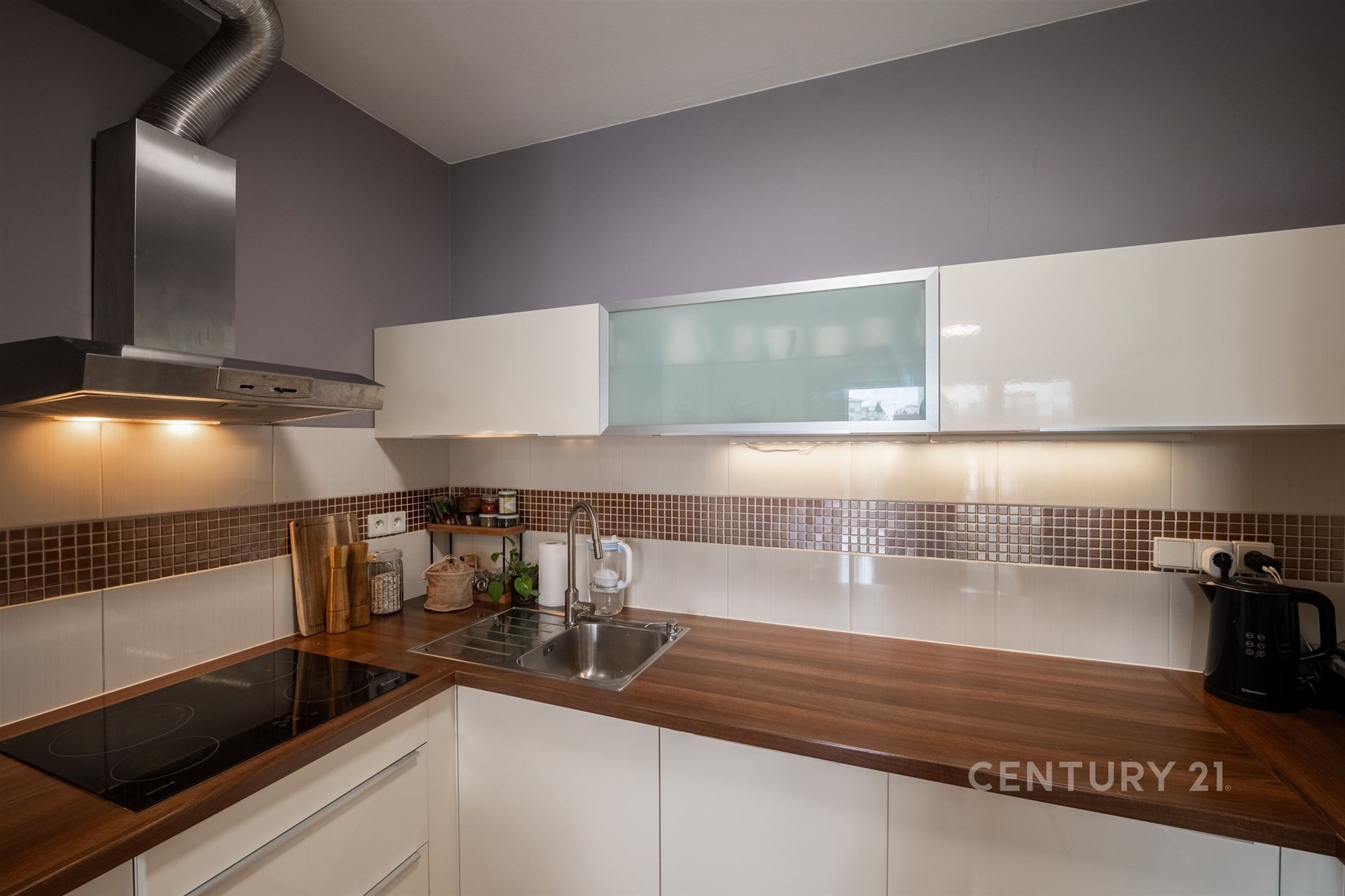 Moderní kuchyň s dřevěnou pracovní deskou, vestavěnými spotřebiči a keramickým obkladem, elegantní a funkční prostor.