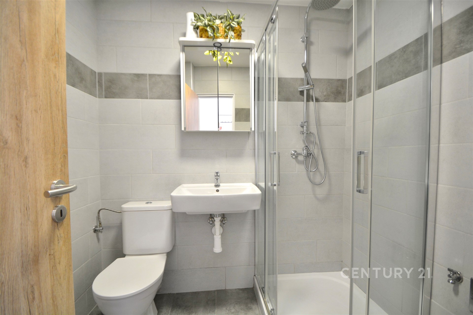 Moderní koupelna s dlažbou, sprchový kout a zrcadlová skříňka, světlé obklady, elegantní design.