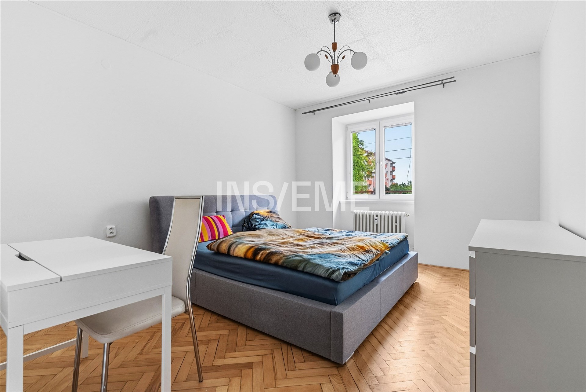 Světlá ložnice s parketovou podlahou, moderním nábytkem a velkými okny, které poskytují dostatek přirozeného světla.