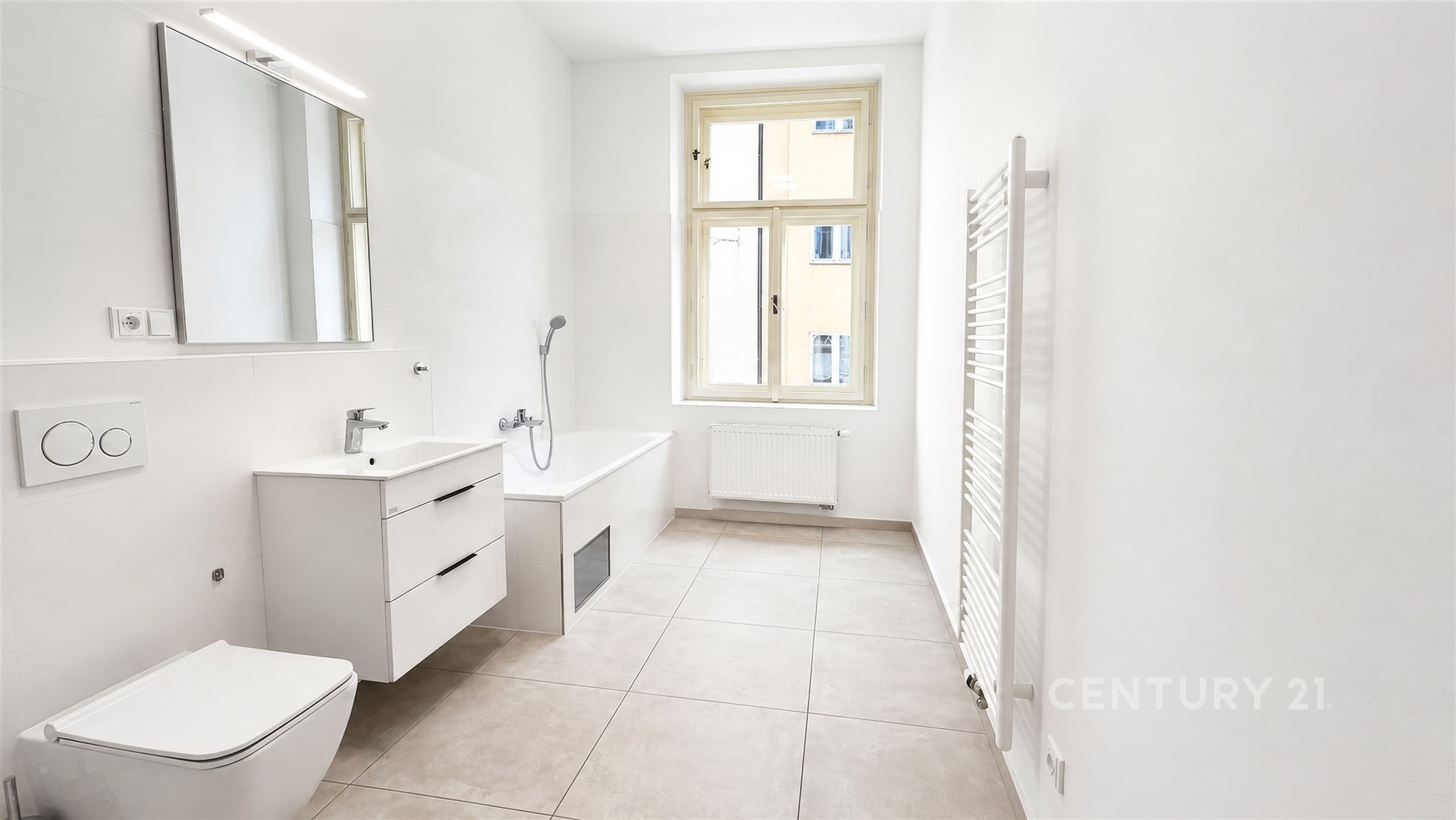 Světlá koupelna s moderní keramickou dlažbou, velkým oknem a nástěnným topením, čistý a minimalistický design.