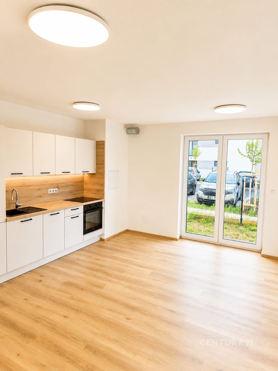 Světlý obývací pokoj s moderní kuchyní, parketová podlaha a velká okna poskytují elegantní a prostorný pocit v nově zrekonstruovaném interiéru.