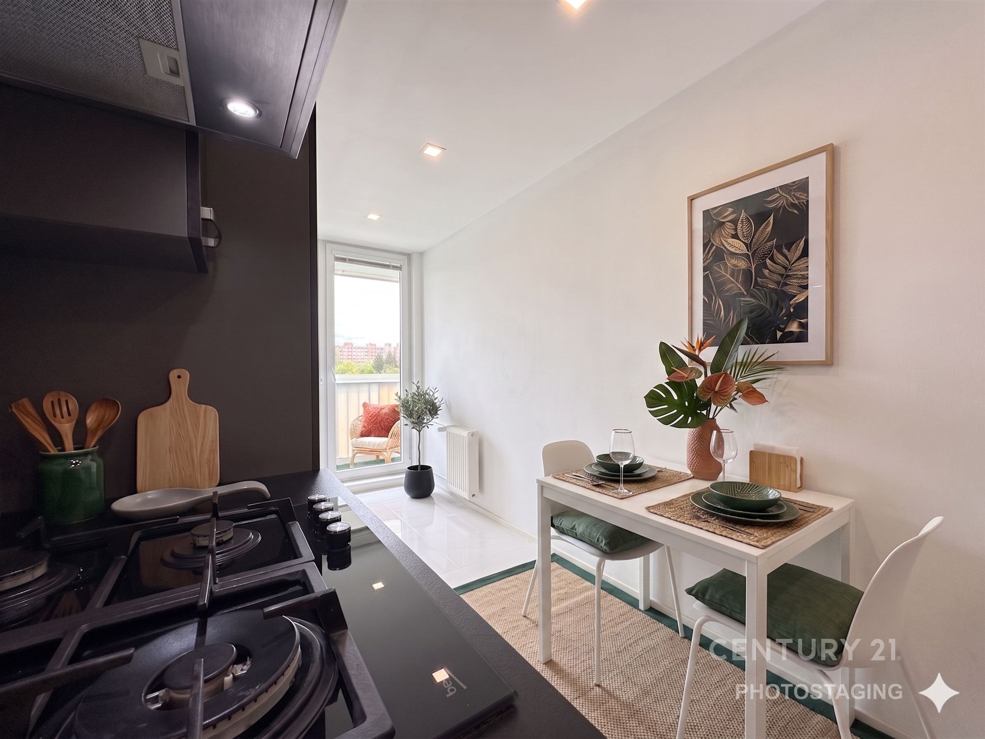 Moderní kuchyň s keramickou dlažbou, elegantní černou pracovní deskou a vestavěnými spotřebiči. Je propojena s jídelním koutem a má přístup na balkon.